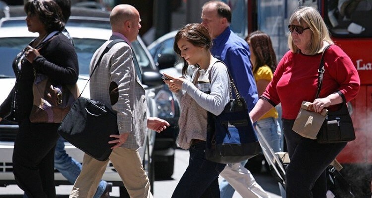 Pessoas na rua com o celular na mão