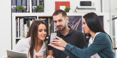 woman-showing-smartphone-to-colleagues_23-2147727665