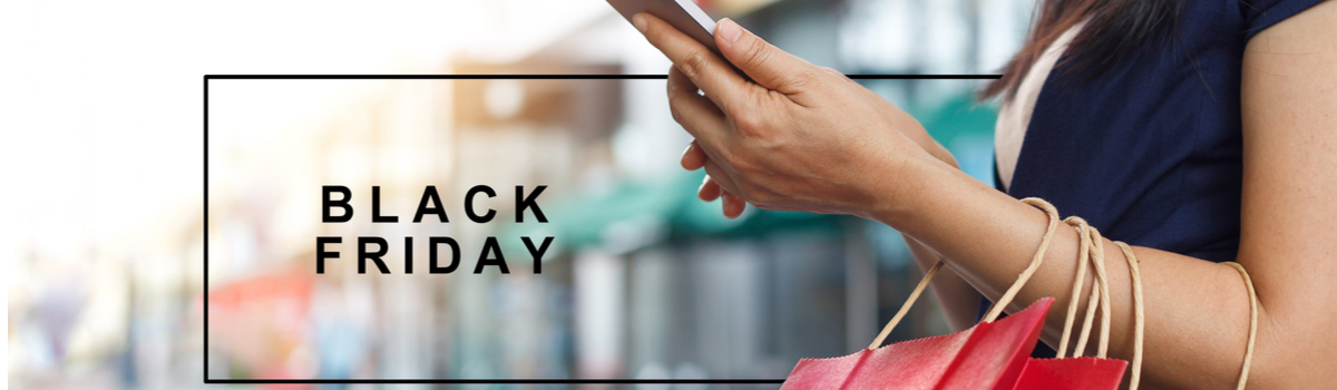 Mão segura um celular e algumas sacolas, sobre fundo desfocado de uma rua, ao lado das palavras Black Friday