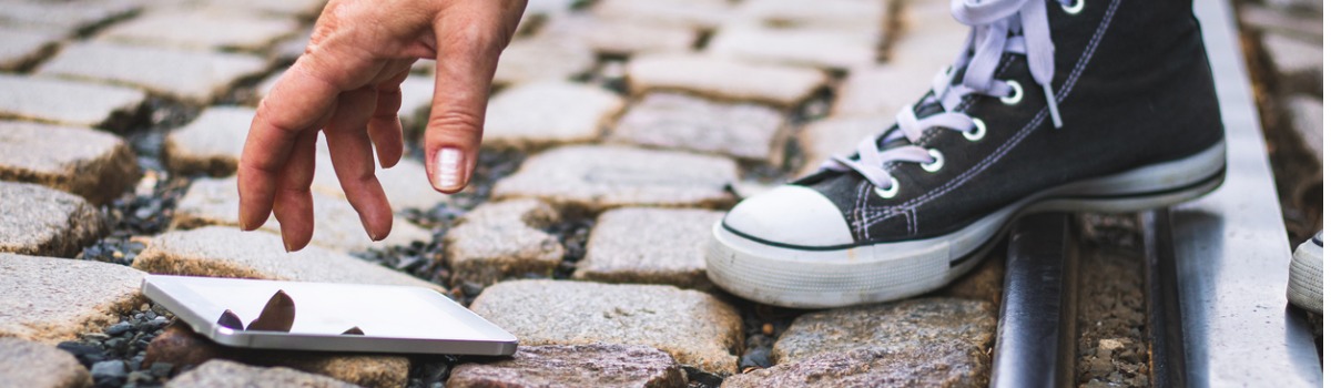 Mão pegando smartphone que caiu no chão.