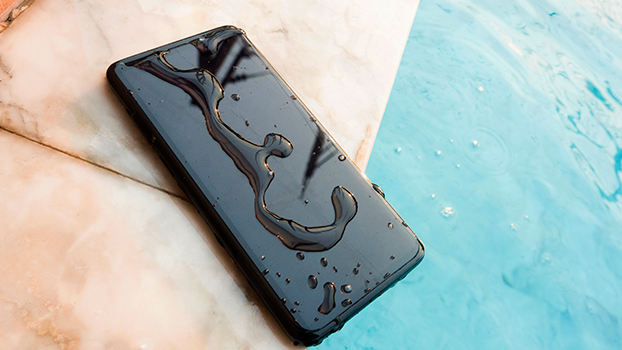 Um celular está na beira da piscina com água em sua tela