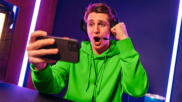 Moço com semblante animado segurando um celular